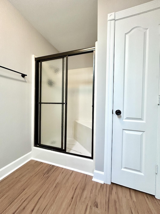 bathroom featuring baseboards, a stall shower, and wood finished floors