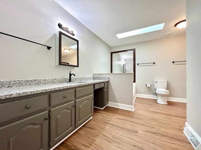 full bathroom featuring visible vents, baseboards, toilet, wood finished floors, and a skylight