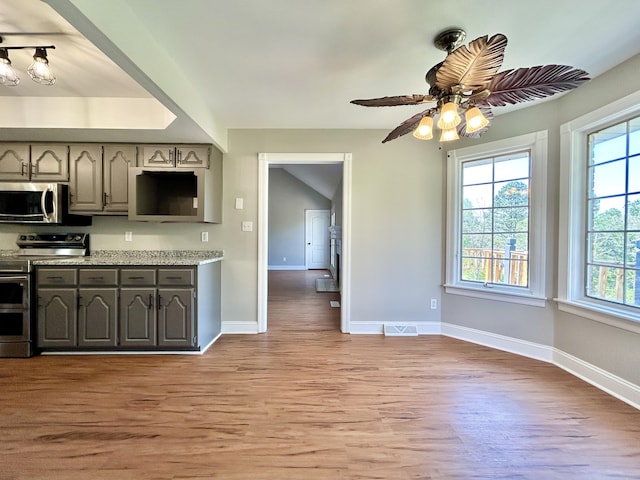 kitchen featuring stainless steel appliances, plenty of natural light, light wood-type flooring, and baseboards