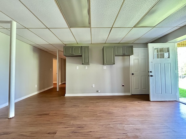 below grade area with a paneled ceiling, wood finished floors, and baseboards