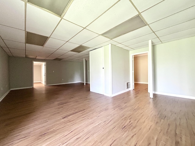 empty room featuring visible vents, baseboards, a paneled ceiling, and wood finished floors