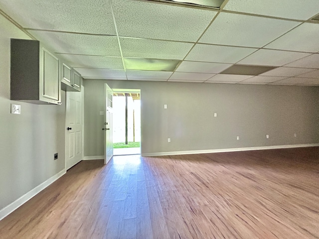 spare room featuring wood finished floors, baseboards, and a drop ceiling