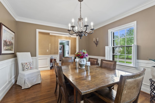 dining area with ornamental molding, a notable chandelier, wainscoting, and wood finished floors