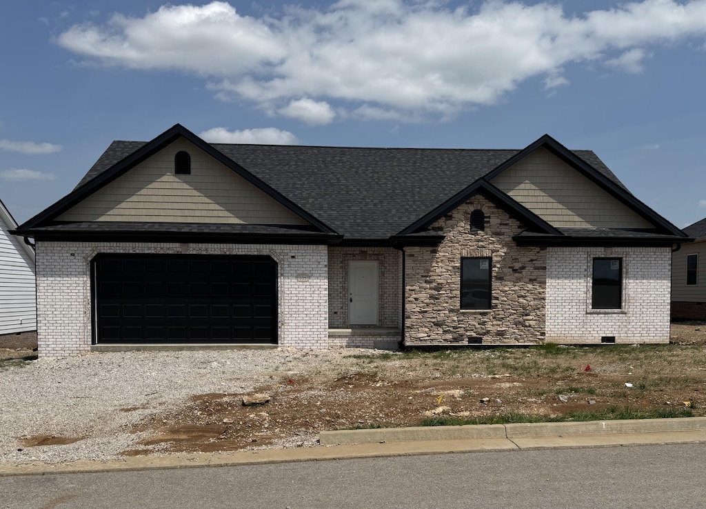 view of front of home featuring brick siding, an attached garage, a shingled roof, and driveway