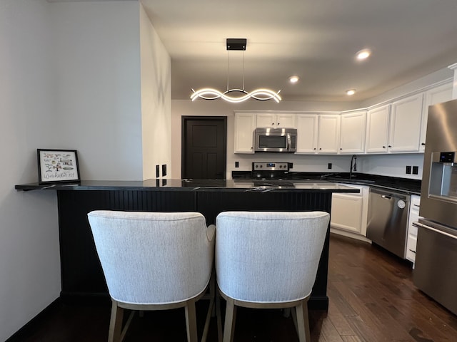 kitchen with a sink, dark countertops, white cabinets, and stainless steel appliances