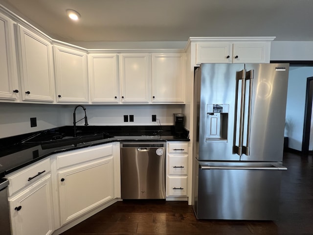 kitchen featuring white cabinetry, appliances with stainless steel finishes, a sink, and dark wood-type flooring