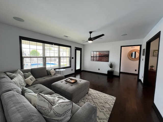 living room with ceiling fan, visible vents, and dark wood finished floors