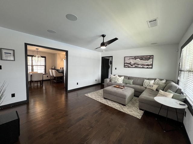 living area featuring plenty of natural light, dark wood-style flooring, ceiling fan, and visible vents
