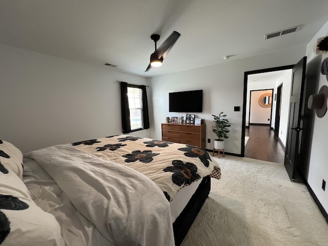bedroom featuring visible vents, a ceiling fan, baseboards, and light carpet