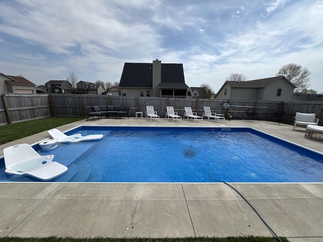 view of swimming pool with outdoor lounge area, a fenced backyard, a fenced in pool, a patio area, and a residential view