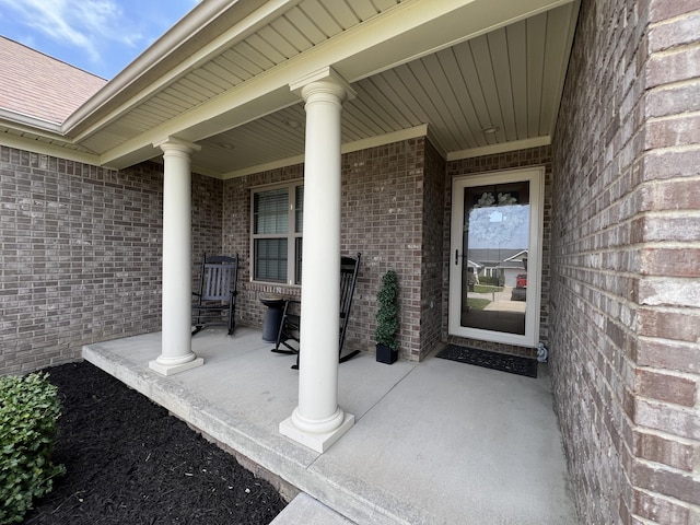entrance to property with a porch and brick siding