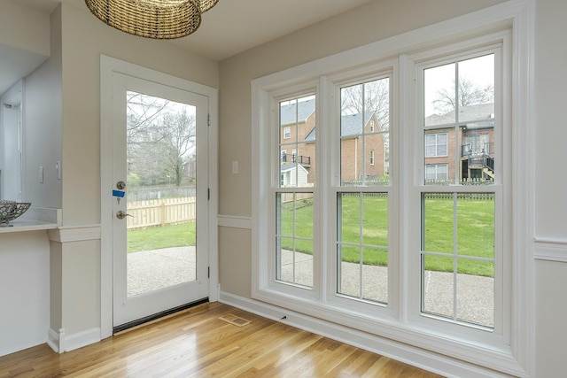 doorway featuring light wood-style flooring, visible vents, and a water view