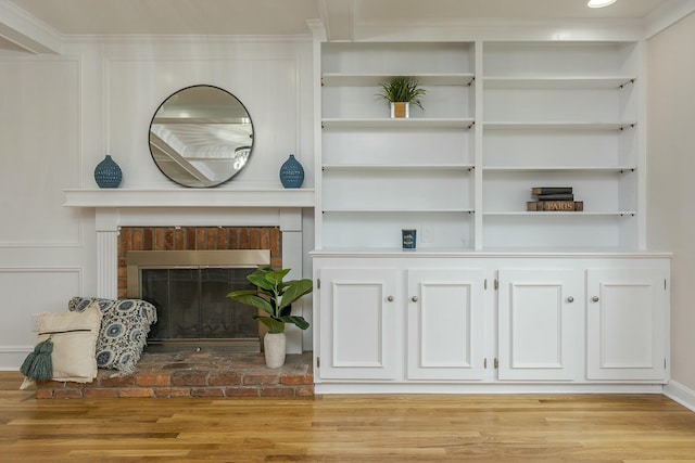 living area featuring light wood finished floors, a fireplace, and built in shelves
