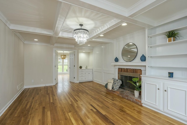 unfurnished living room with a chandelier, a fireplace, ornamental molding, and wood finished floors