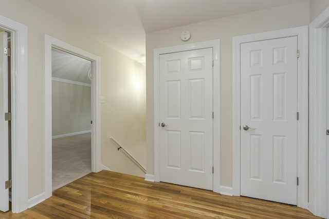 hall featuring an upstairs landing, baseboards, and wood finished floors