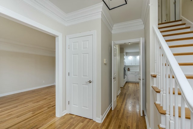hall featuring stairway, light wood-style flooring, baseboards, and ornamental molding