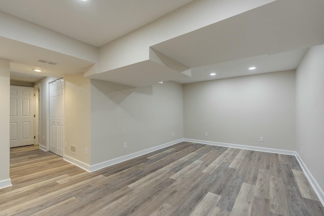 finished below grade area with recessed lighting, light wood finished floors, visible vents, and baseboards