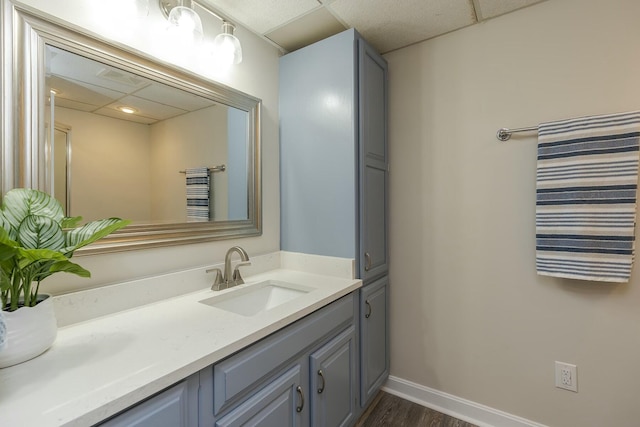 bathroom with a drop ceiling, vanity, baseboards, and wood finished floors