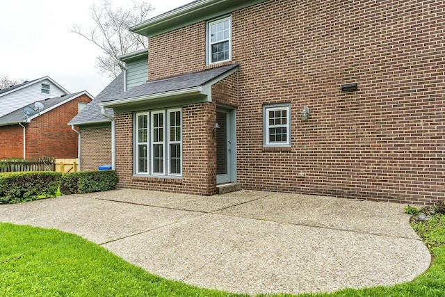 rear view of property with brick siding, fence, and a patio