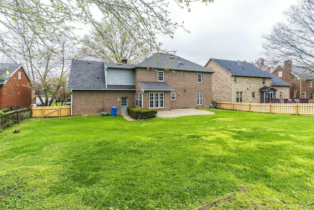 back of house with a patio area, brick siding, a fenced backyard, and a yard