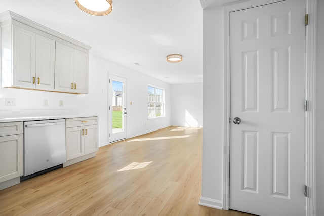 kitchen featuring baseboards, open floor plan, dishwashing machine, light countertops, and light wood finished floors