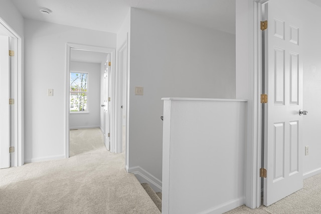 hall with baseboards, carpet flooring, and an upstairs landing