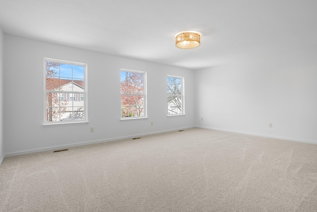 empty room featuring light colored carpet, baseboards, and visible vents