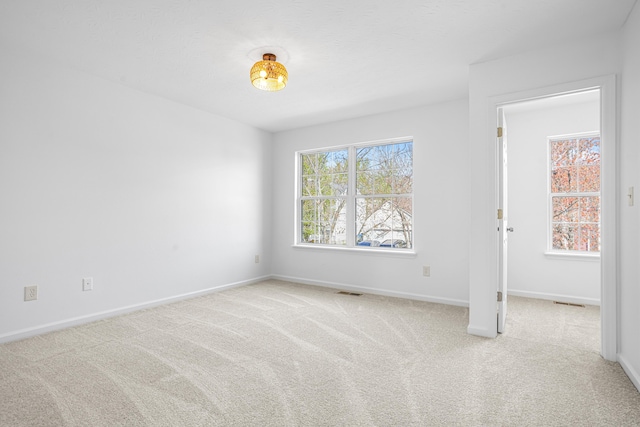 spare room with baseboards, carpet flooring, and visible vents