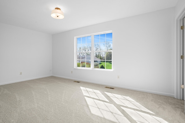 carpeted spare room featuring visible vents and baseboards