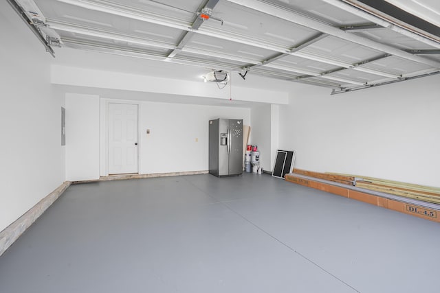 garage with stainless steel refrigerator with ice dispenser and a garage door opener