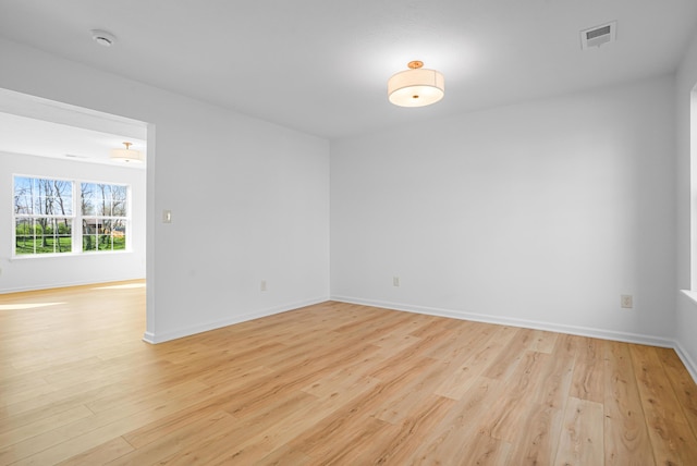 spare room featuring baseboards, light wood-type flooring, and visible vents