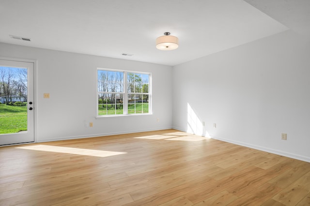 empty room featuring light wood-style floors, baseboards, and visible vents