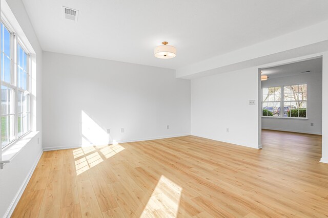 spare room with light wood-style floors, baseboards, and visible vents