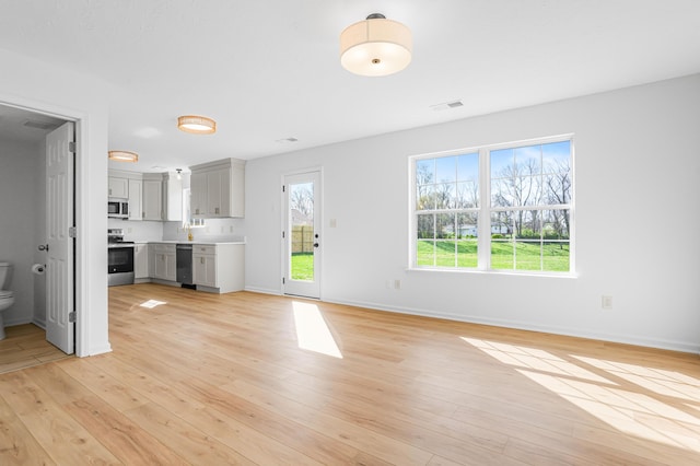 unfurnished living room featuring light wood-style floors, baseboards, and visible vents