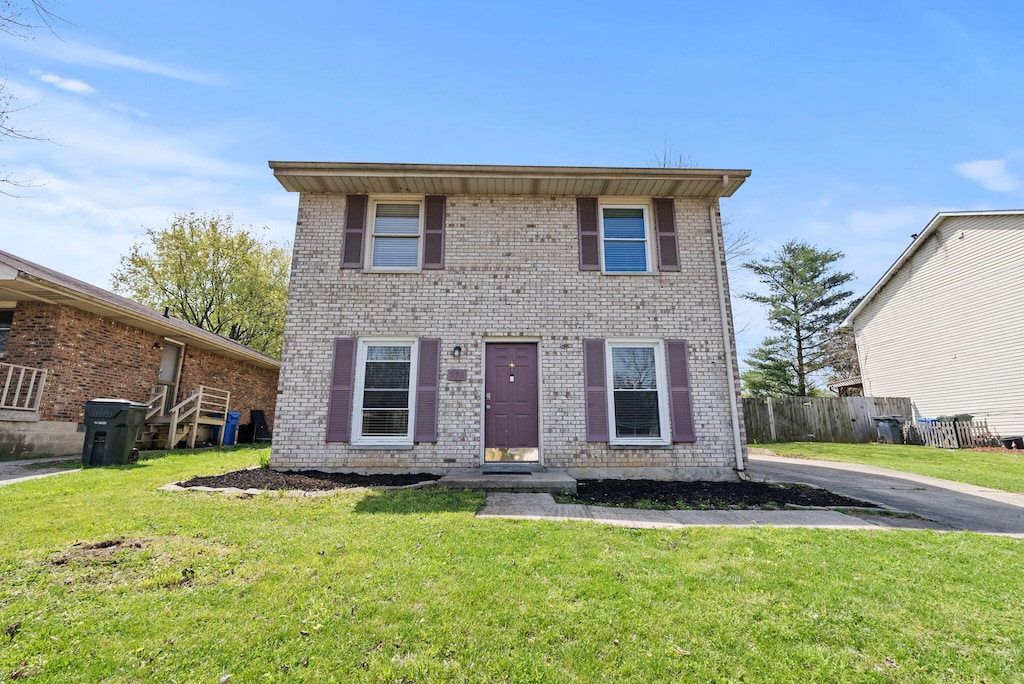 view of front of house featuring a front yard, brick siding, and fence