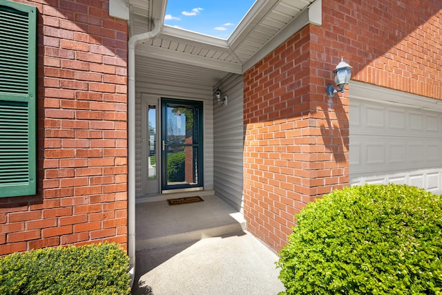 doorway to property featuring a garage and brick siding