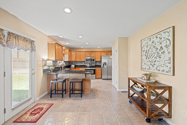 kitchen featuring dark countertops, decorative backsplash, a peninsula, appliances with stainless steel finishes, and recessed lighting