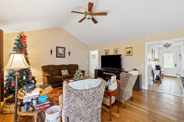 living room with ceiling fan, baseboards, light wood-style floors, and lofted ceiling