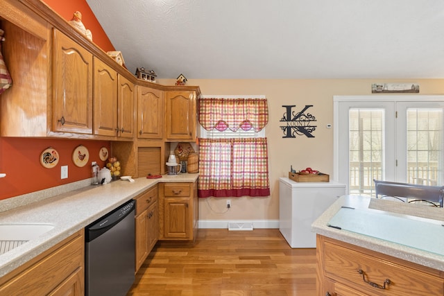 kitchen with light wood-type flooring, dishwasher, light countertops, and visible vents