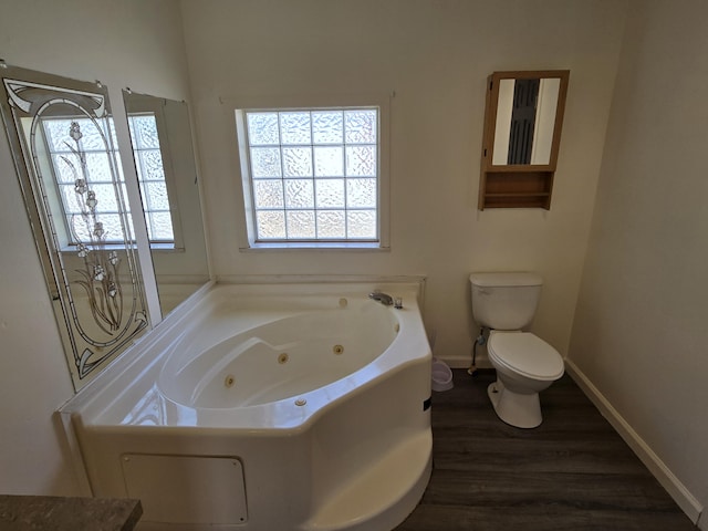 bathroom with a whirlpool tub, wood finished floors, toilet, and baseboards