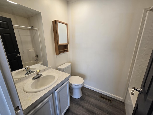 bathroom featuring wood finished floors, vanity, toilet, visible vents, and bathing tub / shower combination