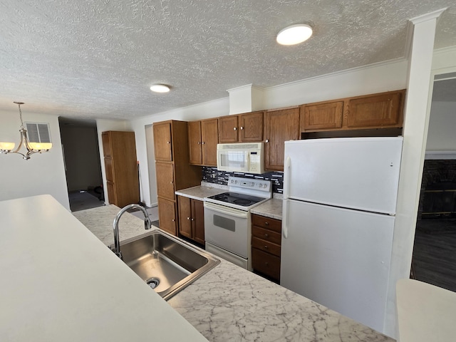 kitchen with an inviting chandelier, light countertops, a sink, white appliances, and a textured ceiling