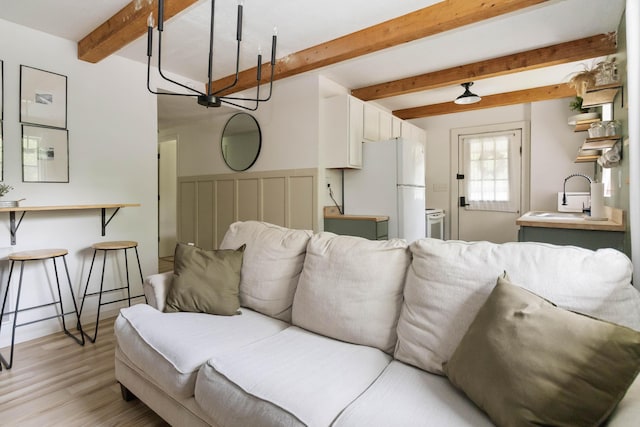 living area with light wood-type flooring and beamed ceiling