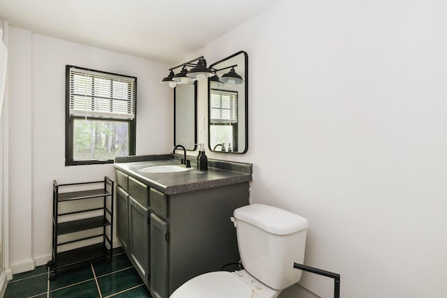 bathroom with toilet, a healthy amount of sunlight, vanity, and tile patterned floors