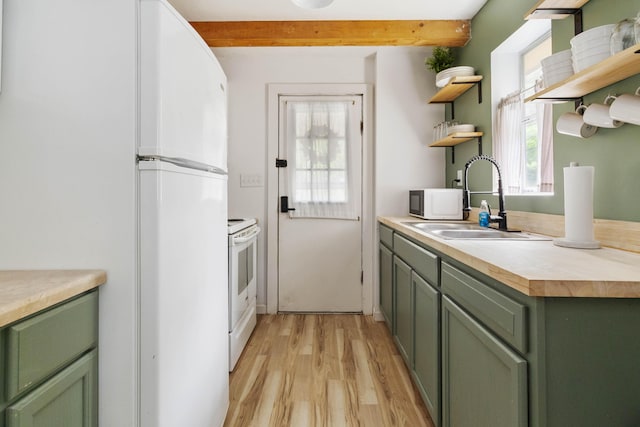 kitchen featuring green cabinetry, open shelves, a sink, white appliances, and light wood-style floors