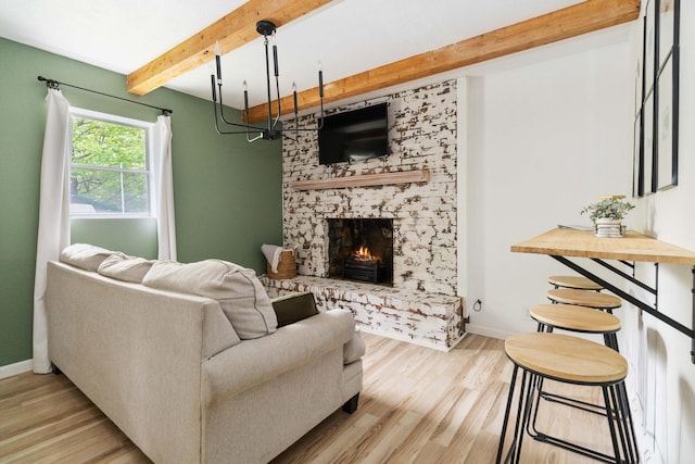 living room with a stone fireplace, wood finished floors, beam ceiling, and baseboards