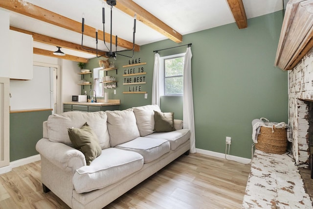 living area featuring a fireplace, baseboards, beam ceiling, and light wood-style floors