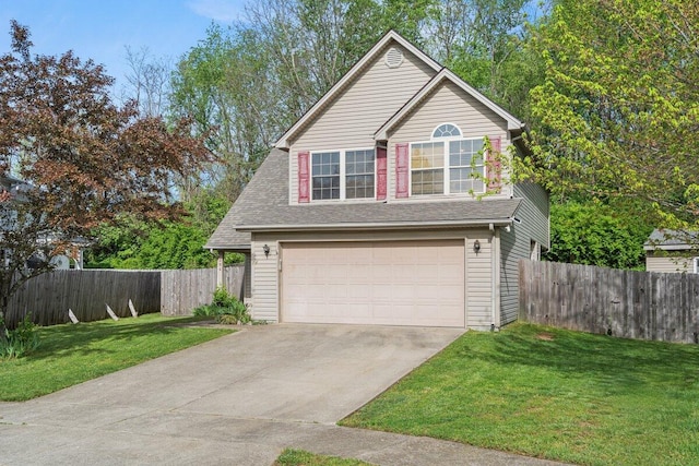 traditional-style home featuring a front lawn, fence, driveway, and an attached garage