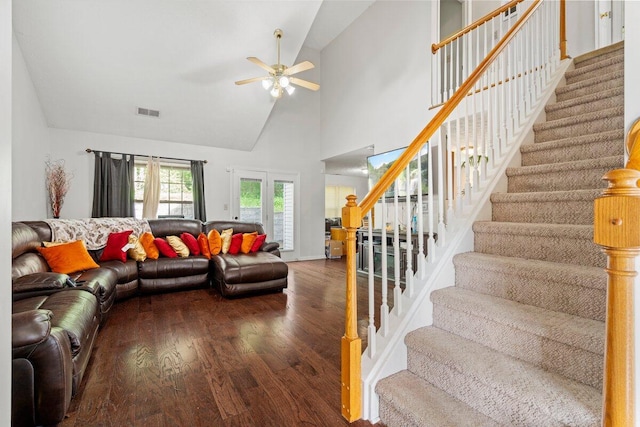 living room with visible vents, a ceiling fan, wood finished floors, stairs, and high vaulted ceiling