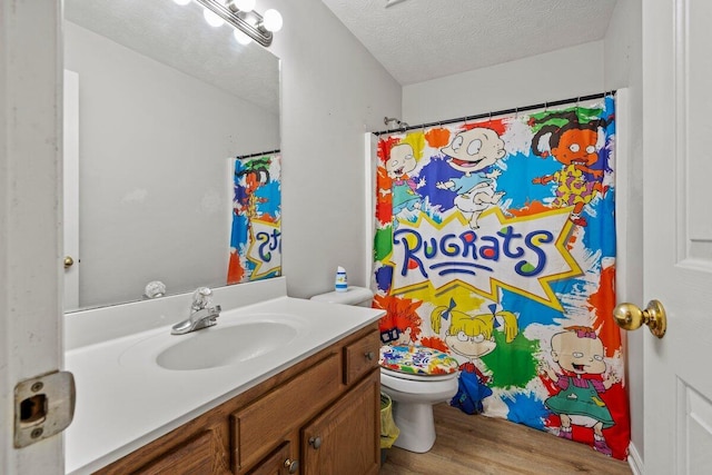 full bathroom with wood finished floors, toilet, vanity, a shower with shower curtain, and a textured ceiling